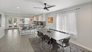 A spacious kitchen with a central island, a dining area with a long table and chairs, and a ceiling fan. - Bright Modern Home in Central Phx w/ Private Yard 8min to Airport & Downtown (Phoenix)