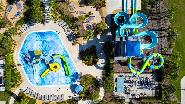 Vista aérea de un parque acuático con piscina, toboganes y zona de juegos.