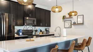 Una cocina moderna con armarios oscuros, electrodomésticos de acero inoxidable y una isla grande con taburetes de bar.