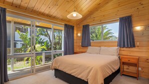 Une chambre avec un grand lit, un plafond en bois et une vue sur la verdure.