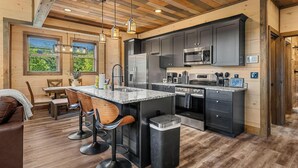 A modern kitchen with dark cabinets, stainless steel appliances, and a bar area with stools. - Peaceful Paradise (Sevierville)