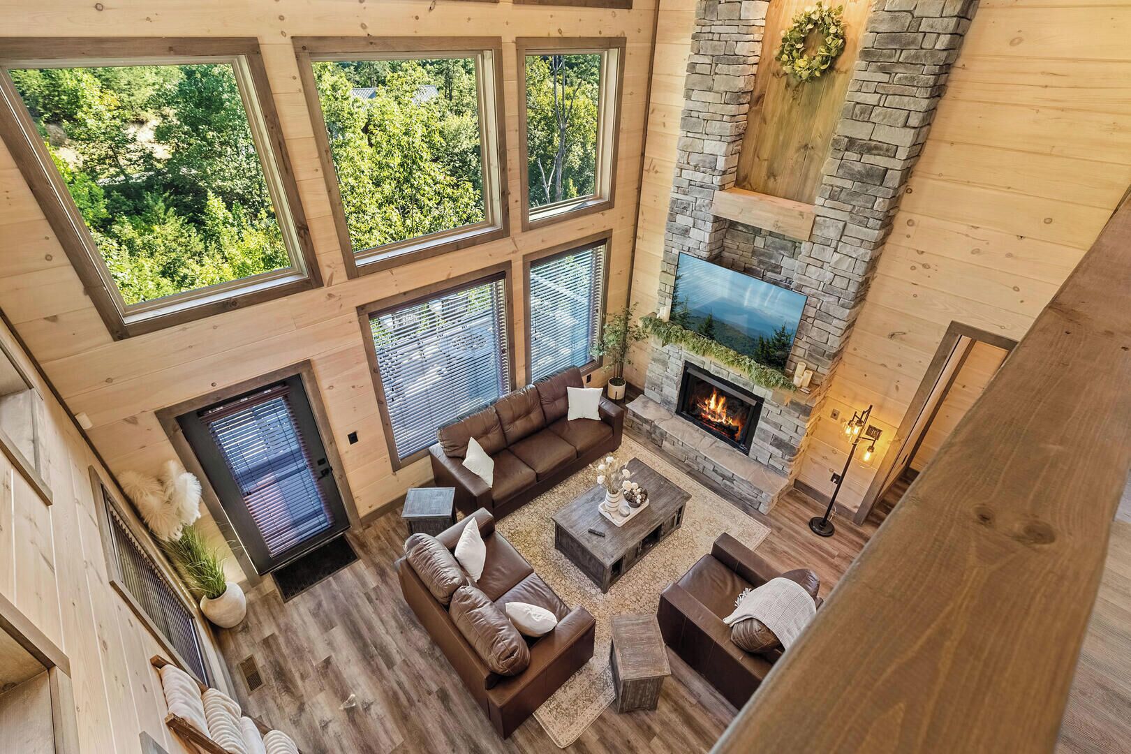 A spacious living area with a stone fireplace, large windows, and a cozy seating arrangement.
