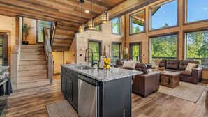 A spacious kitchen with a central island, large windows, and a staircase leading to an upper level. - Peaceful Paradise (Sevierville)