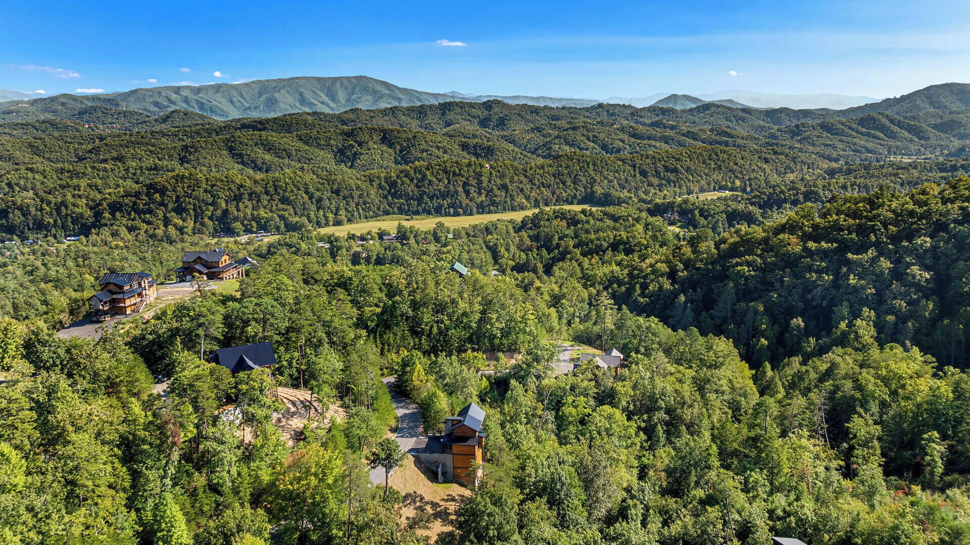 Un paisaje montañoso con un grupo de cabañas y una posada.