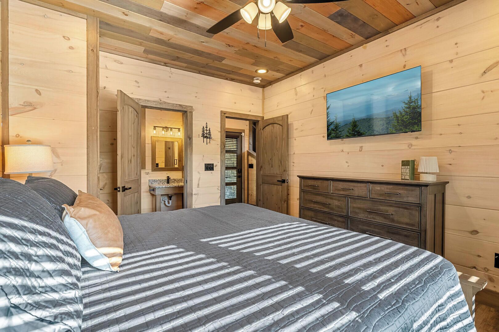 A bedroom with a bed, dresser, and a painting of a landscape.