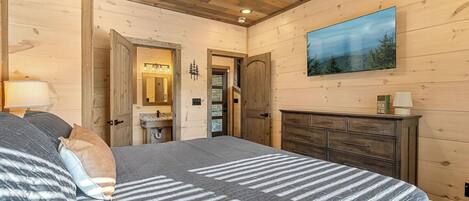 A bedroom with a bed, dresser, and a painting of a landscape.