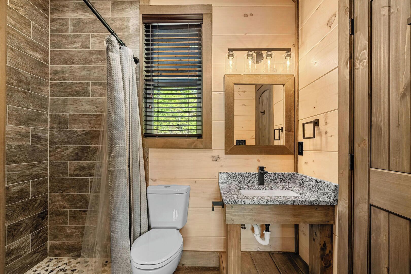 A bathroom with a shower, toilet, and sink.