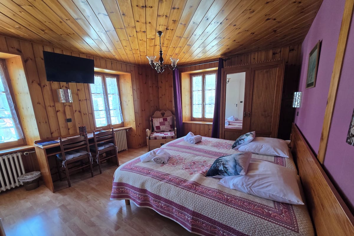Um quarto com painéis de madeira, uma cama, uma mesa e uma cadeira.
