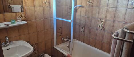 A bathroom with a sink, bidet, and bathtub.