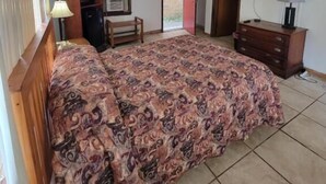 A bedroom with a bed, a desk, a television, and a sliding door to a balcony. - Daniel's Motel (La Salle)