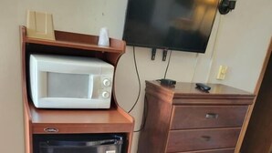 A compact kitchenette with a microwave, refrigerator, and a wooden cabinet with drawers. - Daniel's Motel (La Salle)
