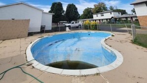 A swimming pool in a residential area with houses in the background. - Daniel's Motel (La Salle)