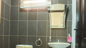 Een badkamer met toilet, wastafel en spiegel.