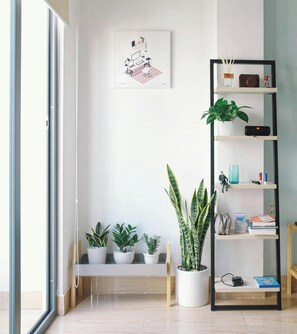 Une pièce avec un banc, des plantes en pot, une bibliothèque et un tableau encadré au mur.