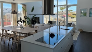 Een moderne keuken met een centraal eiland, een eethoek en grote ramen met uitzicht op de omgeving.