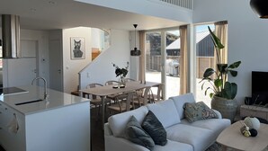 Een moderne keuken met een eethoek, een witte bank en een groot raam met gordijnen.