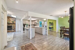 Eine geräumige Küche mit Kochinsel, ein Essbereich mit Holzkästen und ein Wohnzimmer mit Kamin.