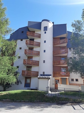 A multi-story building with balconies, a door, and a small sign. - 50m from resort center, 4th floor, view mountain/ski slopes, balcony, tv, 28m², Les 2 Alpes (Les Deux Alpes)