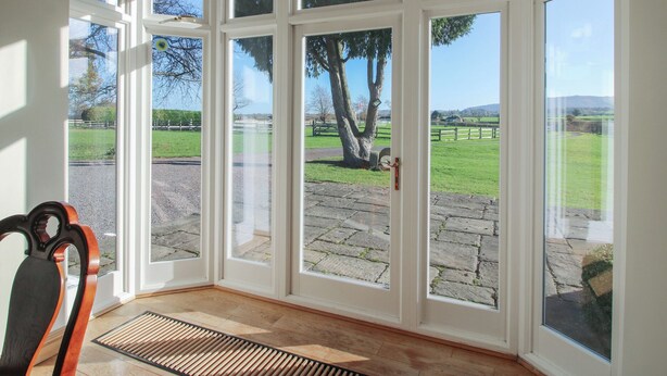 Una habitación con ventanas amplias, una silla y suelo de madera.