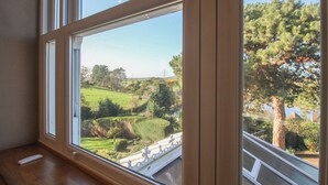 Una habitación con un amplio ventanal que da a un paisaje verde con árboles y una valla.