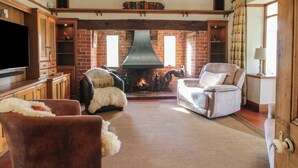 Una sala de estar acogedora con chimenea, sillones de cuero y un televisor de pantalla plana.