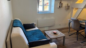 Un salon confortable avec un canapé, une petite table et une fenêtre avec des rideaux.