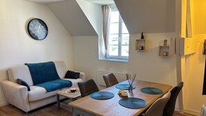 Un salon chaleureux avec une table à manger en bois, un canapé et une horloge au mur.