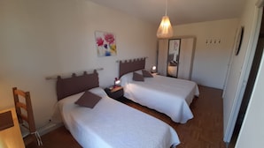 A bedroom with two beds, a wooden floor, a painting on the wall, and a mirror. - Bright T2 with Wi-Fi and washing machine, center of La Roche-Posay (La Roche-Posay)