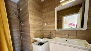 A bathroom with a shower, a sink, and a mirror. - Bright T2 with Wi-Fi and washing machine, center of La Roche-Posay (La Roche-Posay)