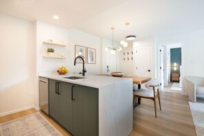 Une cuisine moderne dotée d’un îlot central, de meubles encastrés et d’un coin repas avec une table et des chaises en bois.