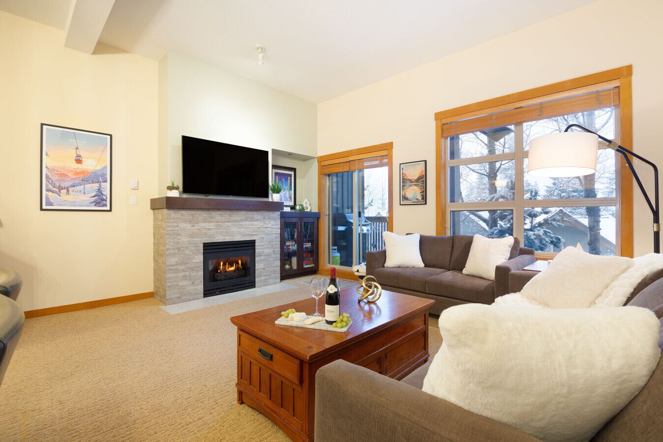 A living room with a fireplace, a sofa, a coffee table, and a TV mounted above the fireplace.