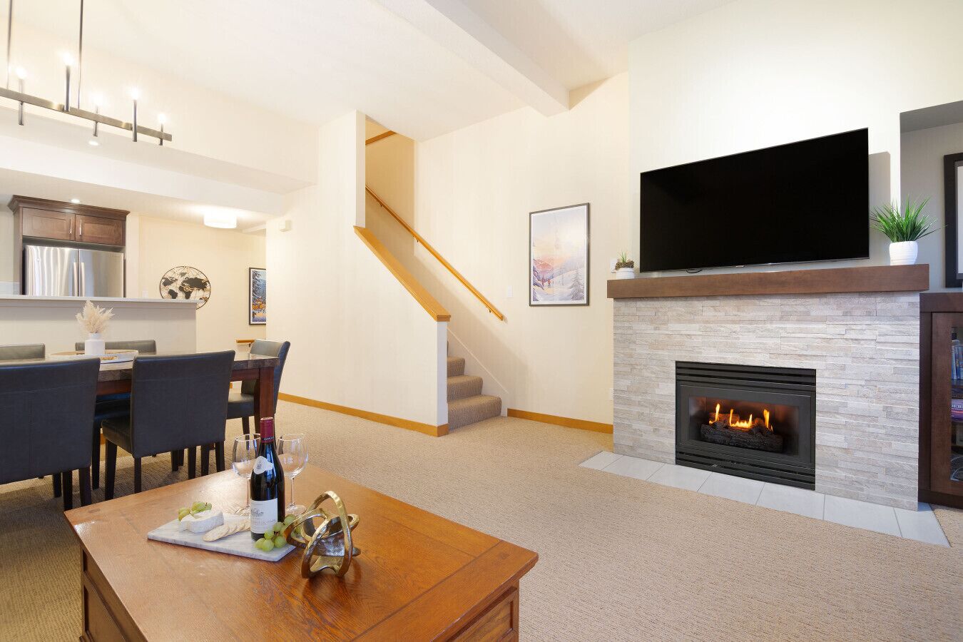 A modern living room with a fireplace, a dining area, and a kitchen in the background.