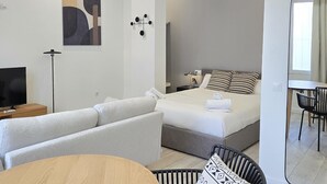 Ein modernes Hotelzimmer mit Bett, einer Couch, einem Schreibtisch und einem Fernseher.