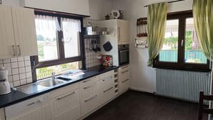 Eine Küche mit weißen Schränken, einer schwarzen Arbeitsplatte, einem Spülbecken, einem Backofen und einem Fenster mit grünen Vorhängen.