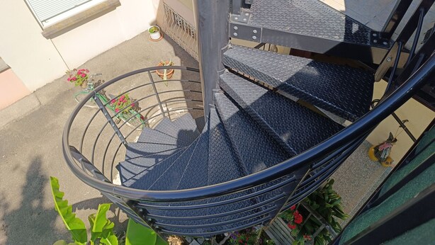 Eine Wendeltreppe mit Metallgeländer und Stufen mit Riffelmuster.
