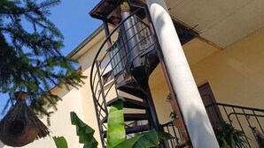 Eine Wendeltreppe mit Metallgeländer, einer weißen Säule und Topfpflanzen.