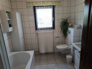 A bathroom with a bathtub, toilet, and radiator. - Cozy lodging with terrace and parking in Jebsheim (Jebsheim)