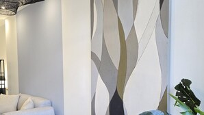 A modern living room with a sofa, armchairs, a round table, and a large abstract wall mural. - Designer Suites in Málaga, Authentic District (Málaga)