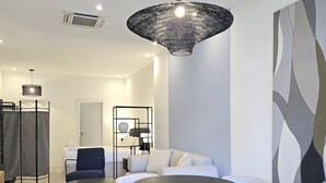 A modern living room with a sofa, two round tables, a hanging light fixture, and a decorative wall piece. - Designer Suites in Málaga, Authentic District (Málaga)