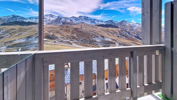 Un balcón con vista a montañas nevadas y cielo despejado.