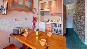 Una cocina compacta con armarios de madera, horno empotrado y cafetera.