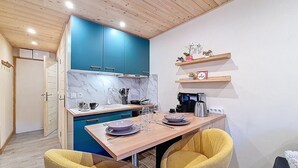 Uma cozinha compacta com armários azuis, uma mesa de madeira e duas cadeiras amarelas.