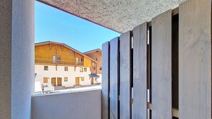 Um corredor estreito com vista para um edifício com várias janelas e uma varanda.