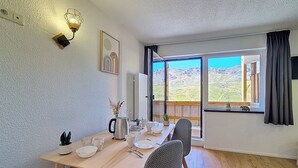En matplats med ett bord dukat för fyra personer, utsikt över bergen genom stora fönster och en modern lampa på väggen.