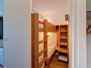A small, compact bedroom with a bunk bed, wooden shelves, and a small table. - Bright studio with south-facing balcony at the foot of the slopes (Val Thorens)