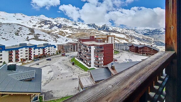 Een hotel met meerdere gebouwen, een parkeerplaats en besneeuwde bergen op de achtergrond.