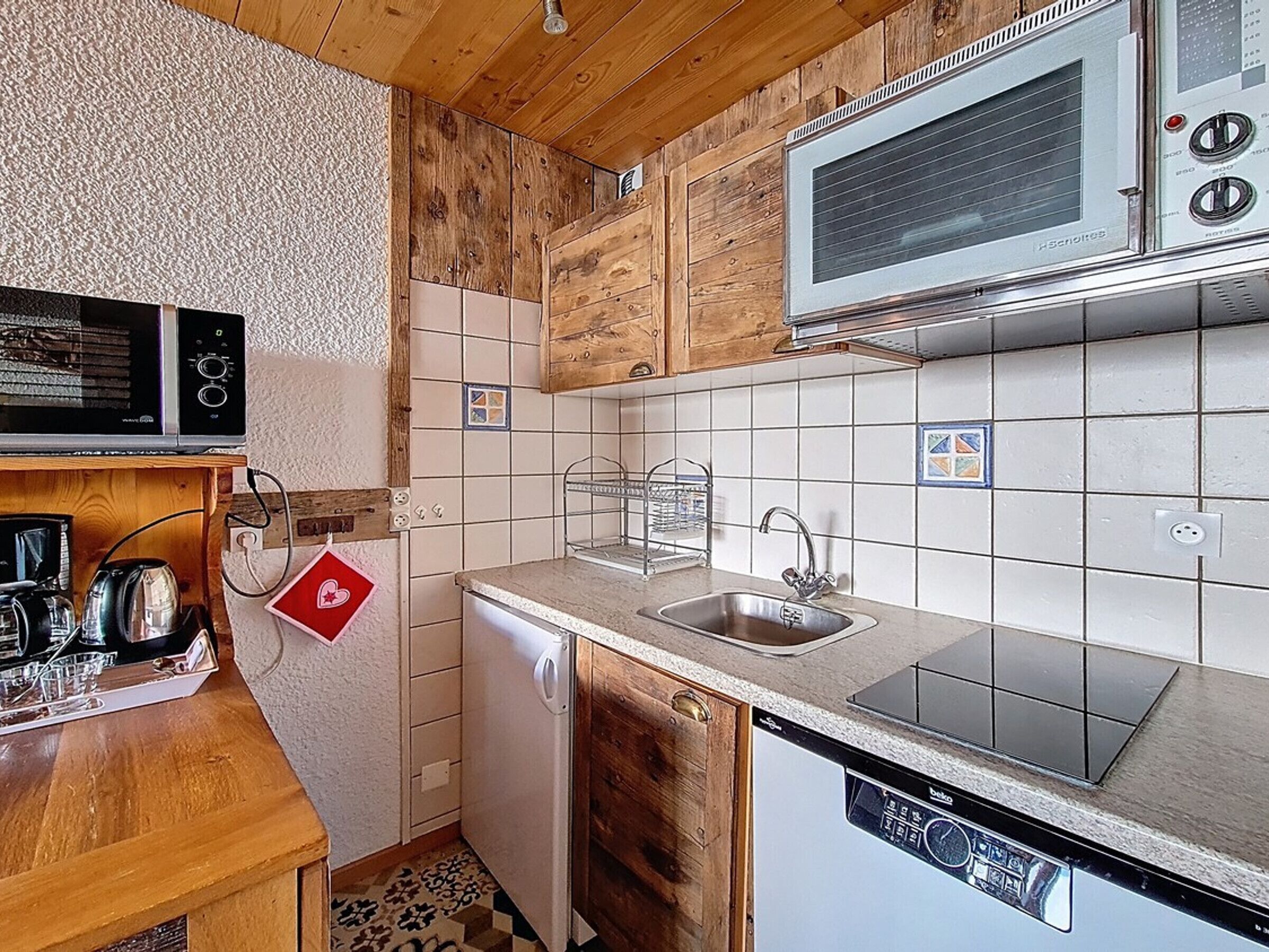 A compact kitchen with a microwave, dishwasher, and sink.