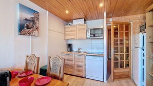 Una cocina compacta con armarios de madera, microondas integrado y lavavajillas.