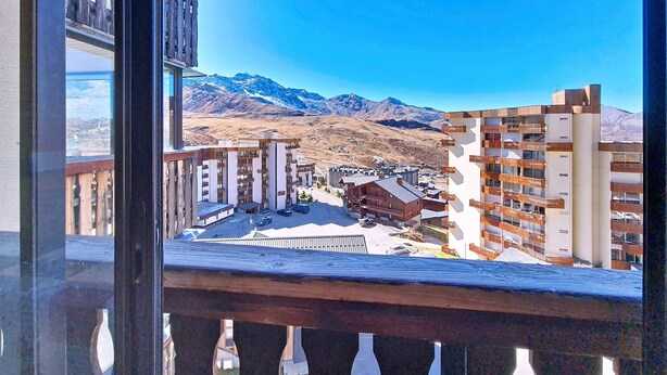 Vista desde un balcón con vistas a un paisaje montañoso y edificios modernos.