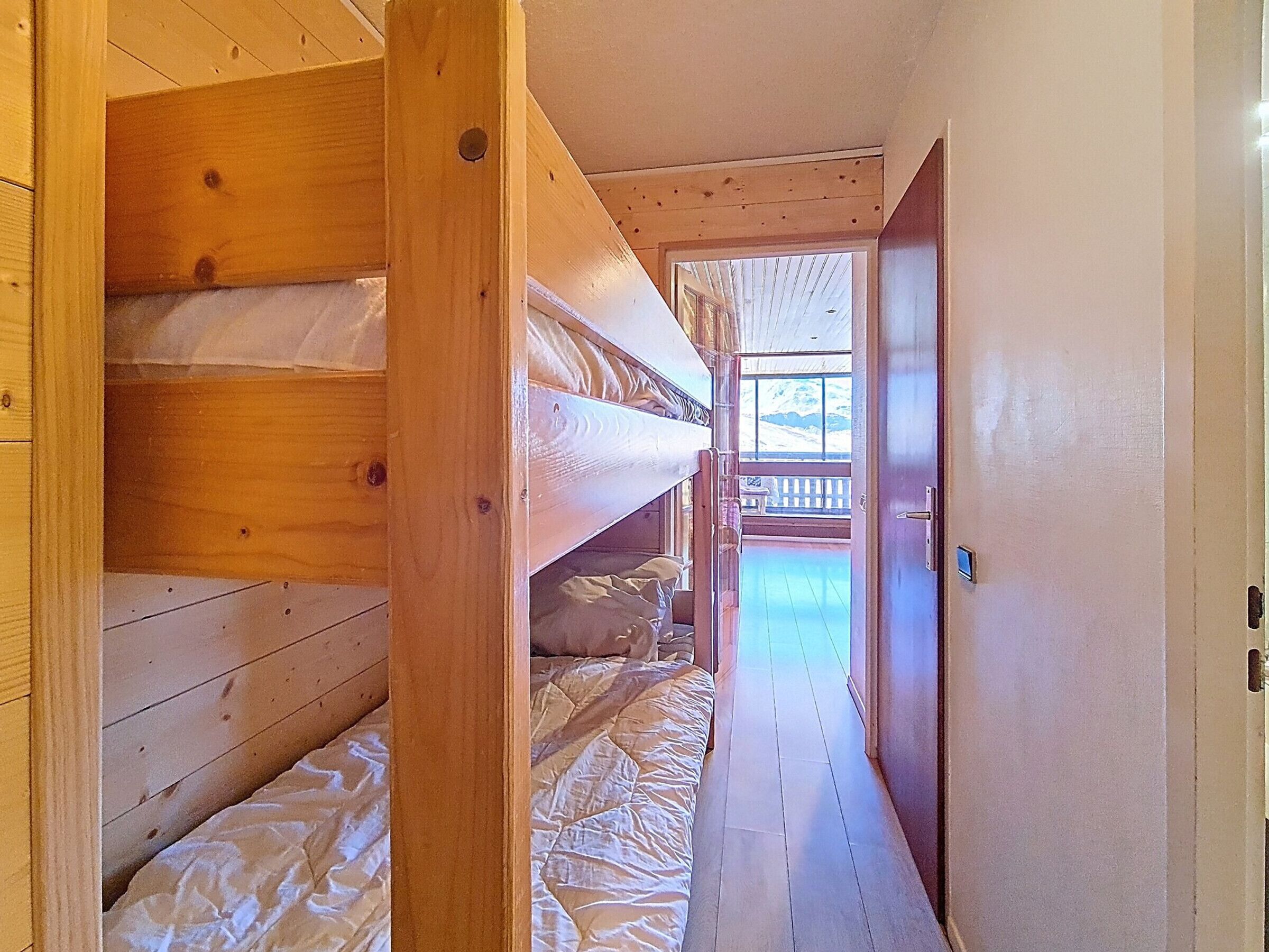 Interior de madera con literas, una puerta que da al exterior y vistas a un balcón.